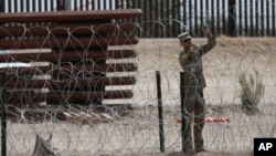 A member of the Texas National Guard installs a barbed-wire barrier on the border between El Paso, Texas and Ciudad Juárez, as seen from Ciudad Juárez, Mexico, May 3, 2023.