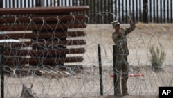 Un miembro de la Guardia Nacional de Texas instala una barrera de alambre de púas en la frontera entre El Paso, Texas y Ciudad Juárez, vista desde Ciudad Juárez, México, el 3 de mayo de 2023.