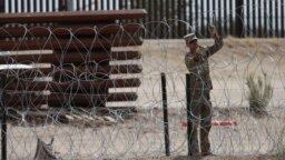 A member of the Texas National Guard installs a barbed-wire barrier on the border between El Paso, Texas and Ciudad Juárez, as seen from Ciudad Juárez, Mexico, May 3, 2023.