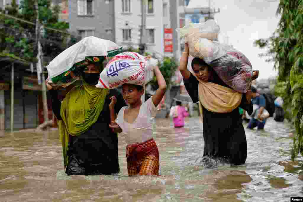 Orang-orang yang membawa pasokan bantuan, mengarungi jalanan yang tergenang banjir di tengah banjir parah yang melanda kota Feni, Bangladesh. (Reuters)&nbsp;