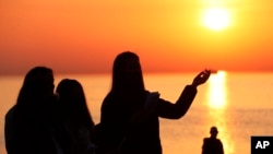 FILE - A parishioner is silhouetted against the rising sun as she prays during an Easter sunrise service held by Park Community Church, April 4, 2021, at North Avenue Beach in Chicago.