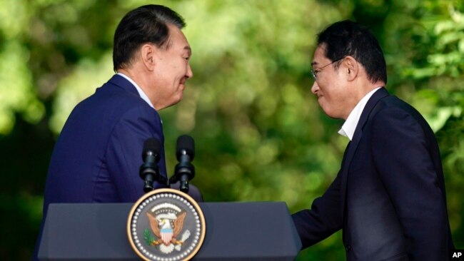 El presidente de Corea del Sur, Yoon Suk Yeol, a la izquierda, estrecha la mano del primer ministro de Japón, Fumio Kishida, después de una conferencia de prensa con el presidente Joe Biden, el 18 de agosto de 2023, en Camp David, cerca de Thurmont, Maryland.