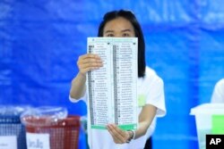 A Thai officer shows a ballot during vote counting at polling station in Bangkok, Thailand, May 14, 2023.