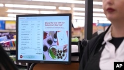 FILE - A woman pays for groceries at a supermarket in Bellflower, Calif., Feb. 13, 2023. 