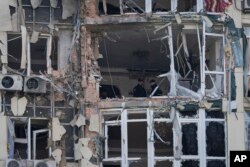 Polisi memeriksa gedung apartemen yang rusak akibat drone, yang ditembak jatuh saat Rusia melakukan serangan semalam, di Kyiv, Ukraina, Senin, 8 Mei 2023. (Foto: AP/Andrew Kravchenko)