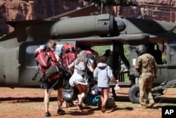 U.S. Army soldiers of the Arizona National Guard guide tourists trapped by flash flooding into a UH-60 Blackhawk, Aug. 24, 2024, on the Havasupai Reservation, Ariz. (Maj. Erin Hannigan/US Army via AP)