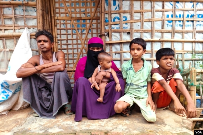 Mohammed Eliyeas, a Rohingya refugee, sits with his wife and children outside their damaged shelter in Cox’s Bazar, Bangladesh, after Cyclone Mocha. The catastrophe has caused great emotional and mental distress to the family, among a million other refugees in the country. (Mohammed Rezuwan Khan/VOA)