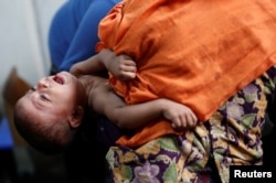 FILE - Md Rasel, a 18 month-old Rohingya refugee child suffering from malnutrition, cries as he is examined by a doctor at the Action Against Hunger centre at Kutupalong camp, near Cox's Bazar, Bangladesh, Jan. 15, 2018.