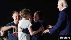 Russian-American journalist Alsu Kurmasheva, who was released from detention in Russia, speaks to her daughters Bibi and Miriam Butorin, and husband Pavel Butorin, as President Joe Biden looks on, at Joint Base Andrews in Maryland, Aug. 1, 2024. 