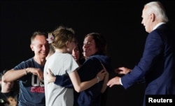 Russian-American journalist Alsu Kurmasheva, who was released from detention in Russia, speaks to her daughters Bibi and Miriam Butorin, and husband Pavel Butorin, as U.S. President Joe Biden looks on, at Joint Base Andrews in Maryland, Aug. 1, 2024.