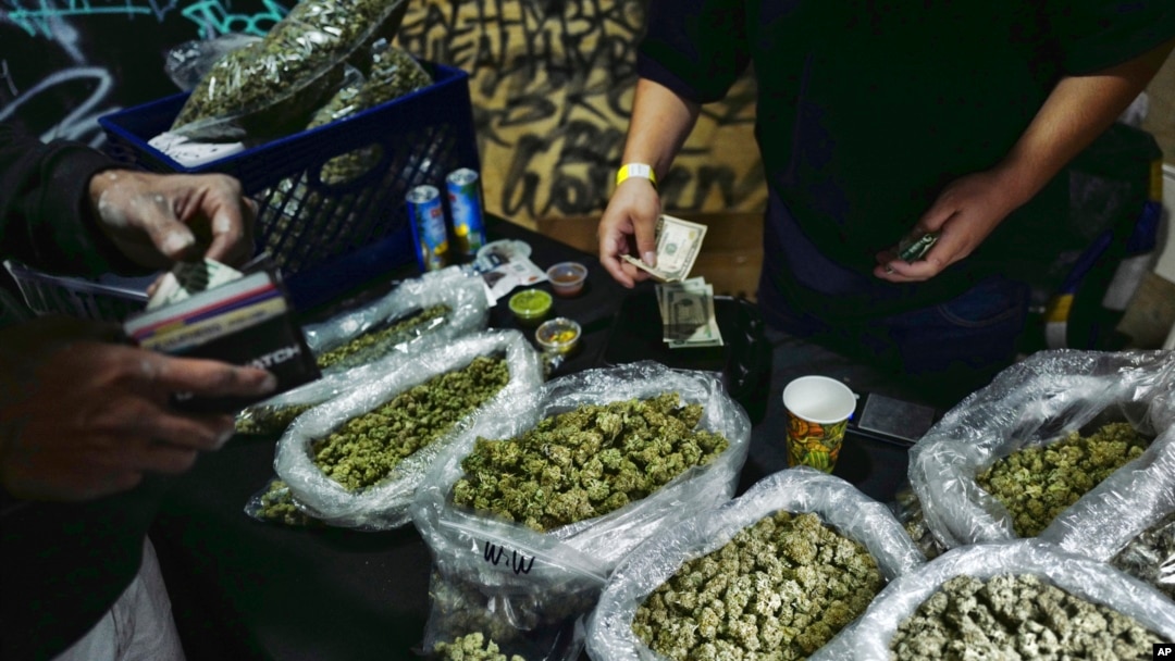 FILE - A vendor makes change for a marijuana customer at a cannabis marketplace in Los Angeles, April 15, 2019. 