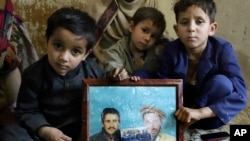 Children of Mohammed Hassan, a Pakistani porter who died on July 27 during a summit of K2, hold a portrait of their father and grandfather in northern Pakistan, Aug. 12, 2023.