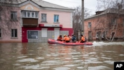 Emergency workers and police ride a boat through a flooded street during evacuations after parts of a dam burst, in Orsk, Russia, April 8, 2024.