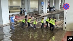 ایرپورٹ کا عملہ عمارت کے باہر جمع ہونے والے پانی کو صاف کر رہا ہے۔ فوٹو اے پی
