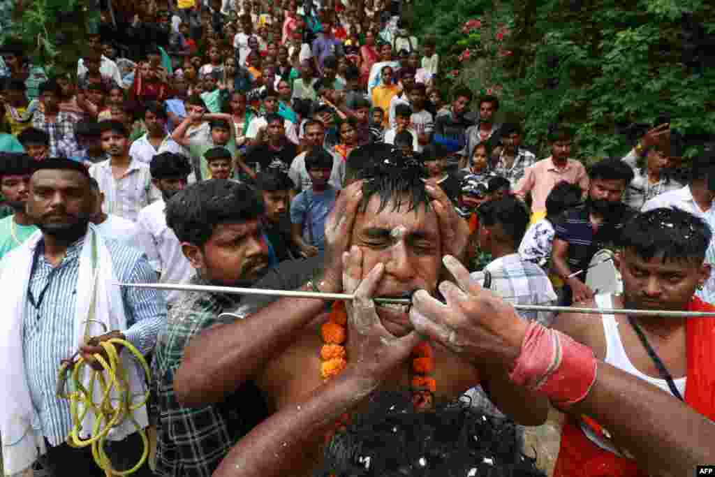 A Hindu devotee gets his cheeks pierced as he takes part in an annual religious procession of goddess Sheetla Mata, in Chandigarh, India.