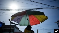 FILE - A vendor prepares his umbrella as hot days continue in Manila, Philippines, April 29, 2024. 