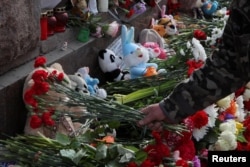A man lays flowers at a makeshift memorial to the victims of a shooting attack at the Crocus City Hall concert venue in the Moscow Region, in Saint Petersburg, March 24, 2024.