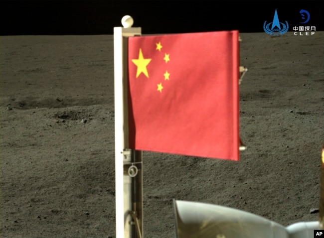 In this China National Space Administration (CNSA) handout image released by Xinhua News Agency, a Chinese national flag carried by the lander of Chang'e-6 probe unfurls at the moon's far side, Tuesday, June 4, 2024. (CNSA/Xinhua via AP)