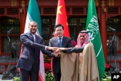 In this photo released by Xinhua News Agency, Iran's Foreign Minister Hossein Amirabdollahian, left, hold hands with his Saudi Arabian counterpart Prince Faisal bin Farhan Al Saud, right, and Chineses counterpart Qin Gang in Beijing Thursday, April 6, 2023.