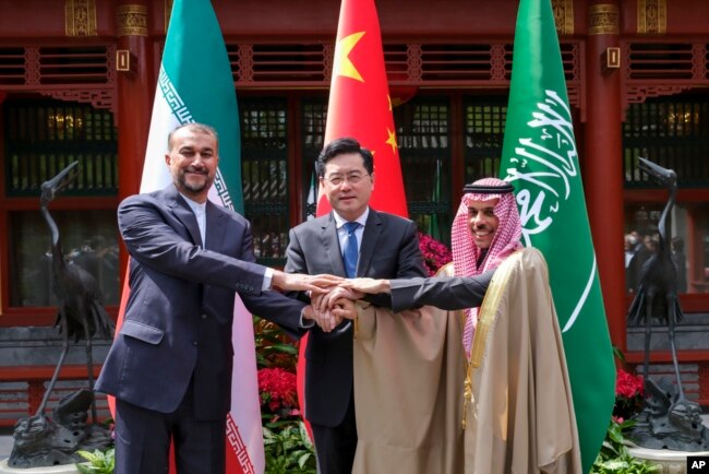 In this photo released by Xinhua News Agency, Iran's Foreign Minister Hossein Amirabdollahian, left, hold hands with his Saudi Arabian counterpart Prince Faisal bin Farhan Al Saud, right, and Chineses counterpart Qin Gang in Beijing Thursday, April 6, 2023.
