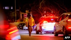 Seorang teknisi taksi swakemudi "Cruise", melepas tanda kerucut di atas kap mobil layanan taksi online yang mogok di San Francisco, California, 11 Juli 2023. (Josh Edelson / AFP)