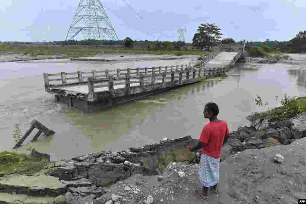 A man watches a bridge over the Motanga River washed away by flash floods following monsoon rains, in Ulubari village of Baska district, some 52 kilometers from Guwahati in India's Assam state.