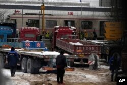 Dua petugas kepolisian berjaga di dekat lokasi tabrakan kereta api di distrik barat di Beijing, Jumat, 15 Desember 2023. (AP/Ng Han Guan)