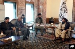 Mullah Abdul Ghani Baradar, the Taliban-appointed deputy prime minister for economic affairs, right, speaks with Pakistan's defense minister, Khawaja Mohammad Asif, during a meeting in Kabul, Feb. 22, 2023.
