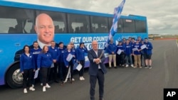 National Party leader Christopher Luxon, who will be New Zealand's next prime minister after a decisive victory in national elections on Oct. 14, 2023, waves a flag in front of supporters in Rotorua. (New Zealand Herald via AP)