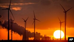 FILE - Steam rises from a coal-fired power plant near wind turbines in Niederaussem, Germany, Nov. 2, 2022. The European Union's fossil fuel energy production hit a record low the first half of the year, according to a think tank.