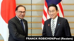 Japanese Prime Minister Fumio Kishida shakes hands with Malaysian Prime Minister Anwar Ibrahim in Tokyo, Japan, Dec. 16, 2023. 