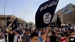 FILE - Demonstrators chant pro-Islamic State group slogans as they carry the group's flags in front of the provincial government headquarters in Mosul, Iraq, June 16, 2014. 