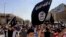 FILE - Demonstrators chant pro-Islamic State group slogans as they carry the group's flags in front of the provincial government headquarters in Mosul, Iraq, June 16, 2014. 