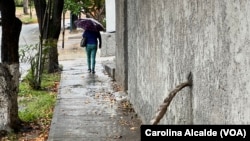 Una mujer se resguarda de la lluvia con un paraguas mientras camina por una calle del este de Caracas el 30 de mayo de 2023. 