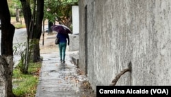 Una mujer se resguarda de la lluvia con un paraguas mientras camina por una calle del este de Caracas el 30 de mayo de 2023. 