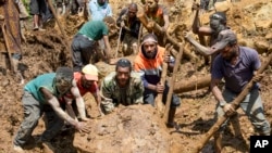 巴布亚新几内亚的村民们在山体滑坡现场移动石块寻找生还者。（2024年5月27日）