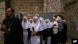 Православное духовенство и монахини со свечами в руках ожидают схождения Благодатного огня в Храме Гроба Господня в Иерусалиме. 15 апреля 2023 года.