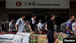 Mainland Chinese visitors line up at Hong Kong's Sheung Shui train station with boxes of instant noodles and packages of diapers to be parallel imported into Shenzhen for resale Aug. 23, 2012.
