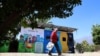 Un hombre pasa frente a unos contenedores de reciclaje en la comuna de Peñalolén, en Chile, que forman parte de las iniciativas impulsadas en este municipio para afrontar la crisis climática.