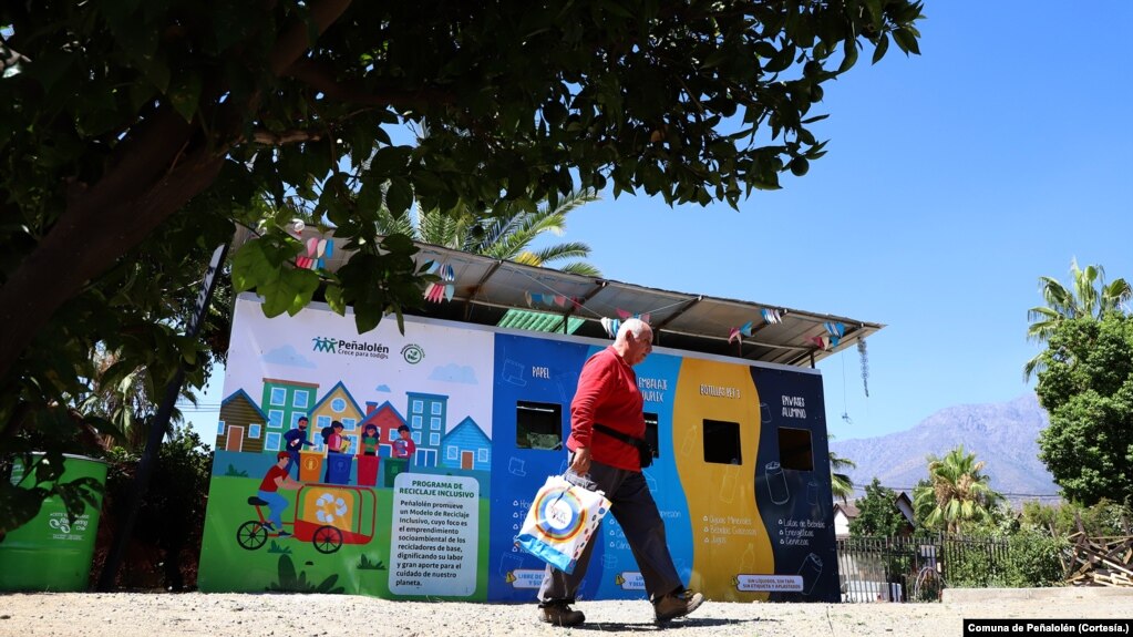 Un hombre pasa frente a unos contenedores de reciclaje en la comuna de Peñalolén, en Chile, que forman parte de las iniciativas impulsadas en este municipio para afrontar la crisis climática.