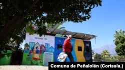 Un hombre pasa frente a unos contenedores de reciclaje en la comuna de Peñalolén, en Chile, que forman parte de las iniciativas impulsadas en este municipio para afrontar la crisis climática.