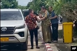 In this image made from video by a source wishing to remain anonymous, one of the two activists, left, traveling with Chinese rights lawyer Lu Siwei, right, argues with police who were in the process of detaining Lu near the Thanaleng dry port, 13 kilometers (8 miles) south of Vientiane, Laos, on July 28, 2023.