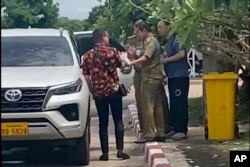 In this image made from video by a source wishing to remain anonymous, one of the two activists, left, traveling with Chinese rights lawyer Lu Siwei, right, argues with police who were in the process of detaining Lu near the Thanaleng dry port, 13 kilometers (8 miles) south of Vientiane, Laos, on July 28, 2023.