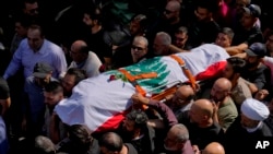 Mourners carry the body of Reuters videographer Issam Abdallah during his funeral procession in his hometown of Khiam, southern Lebanon, Oct. 14, 2023. 