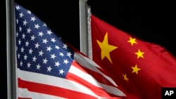 FILE - The American and Chinese flags wave at Genting Snow Park, Feb. 2, 2022, in Zhangjiakou, China. 