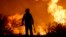 A firefighter is silhouetted by the flames of a fire on the outskirts of Villa Carlos Paz, Argentina, Oct. 10, 2023.