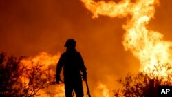 Seorang petugas pemadam kebakaran berdiri di dekat lokasi kebakaran hutan di pinggiran Kota Villa Carlos Paz, Argentina, pada 10 Oktober 2023. (Foto: AP/Nicolas Aguilera)