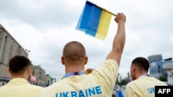 An athlete in the Ukraine delegation holds up a flag ahead of the floating parade on the river Seine during the Paris Olympics opening ceremony in Paris, France, July 26, 2024.