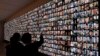 Visitors look at photos of Israeli people who were killed during Hamas militants attack on Oct. 7 and those who died during the Israel-Hamas war in the Gaza Strip, displayed on a giant screen at the National Library in Jerusalem, Jan. 28, 2024. 