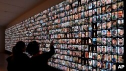 Visitors look at photos of Israeli people who were killed during Hamas militants attack on Oct. 7 and those who died during the Israel-Hamas war in the Gaza Strip, displayed on a giant screen at the National Library in Jerusalem, Jan. 28, 2024. 